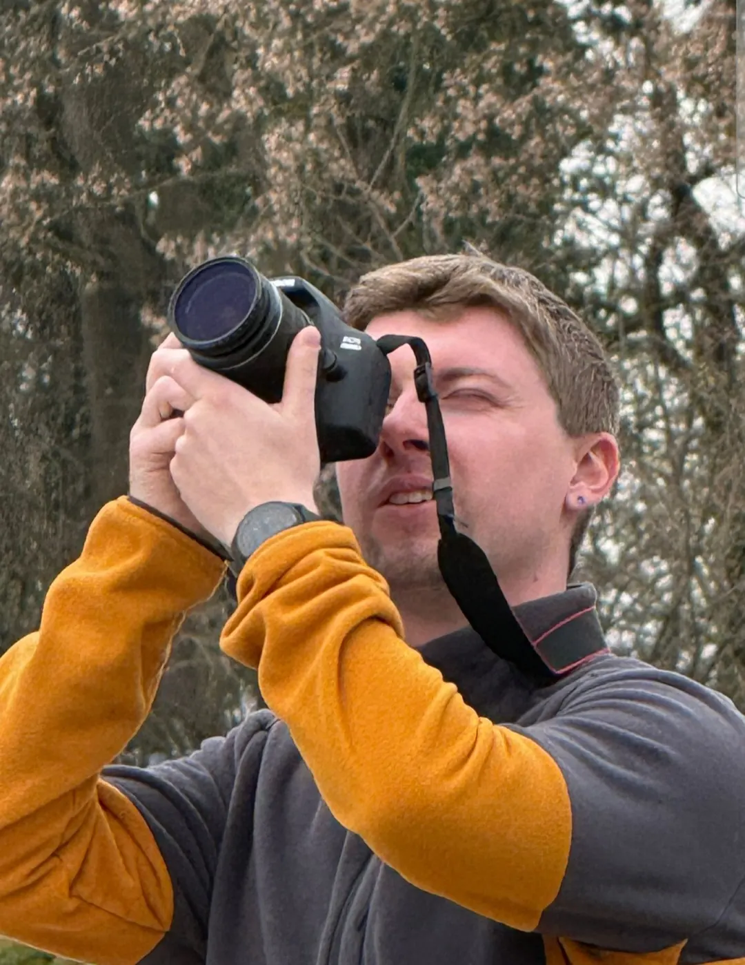 Portrait of an amateur photographer capturing a shot with a DSLR camera and telephoto lens outdoors